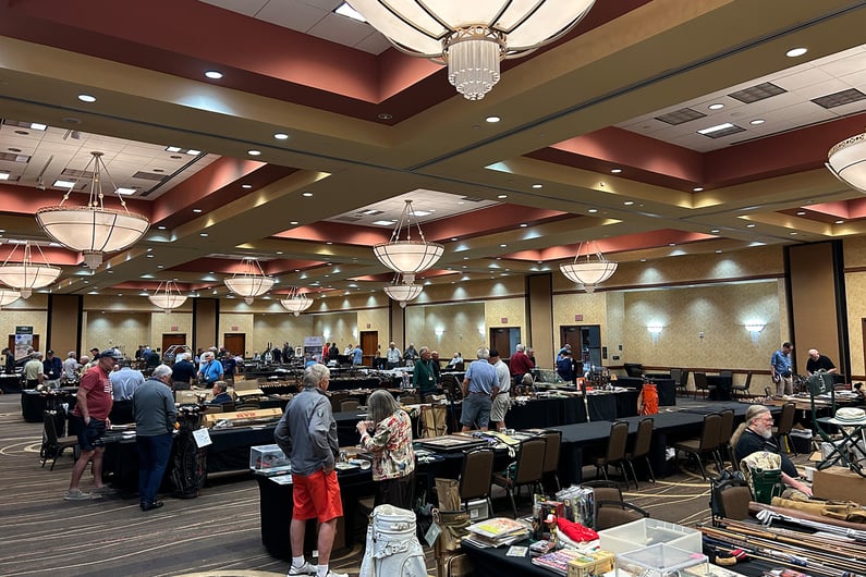 Collectors and golf enthusiasts at the 54th National Convention of the Golf Heritage Society, showcasing vintage golf clubs, memorabilia, and collectibles in a large exhibition hall.