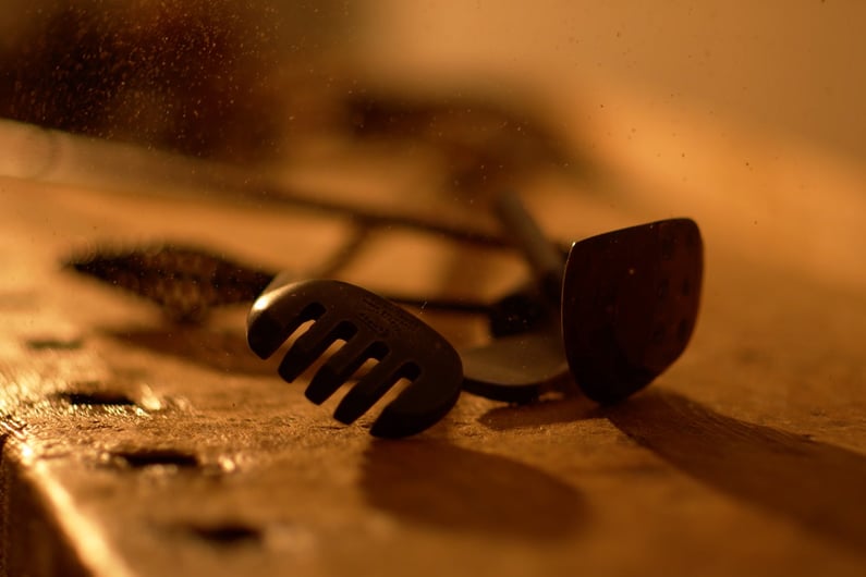 Close-up of a rare vintage golf club head, known as a rake niblick, resting on a wooden workbench in warm light.