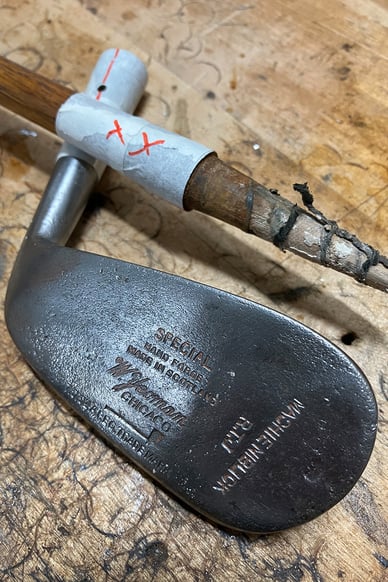 Vintage MacGregor hickory iron head with original markings, photographed during the restoration process on a workshop bench.
