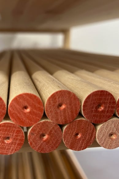 Close-up of newly produced unfinished hickory shafts, stacked on a wooden rack, showing freshly cut ends marked for processing.