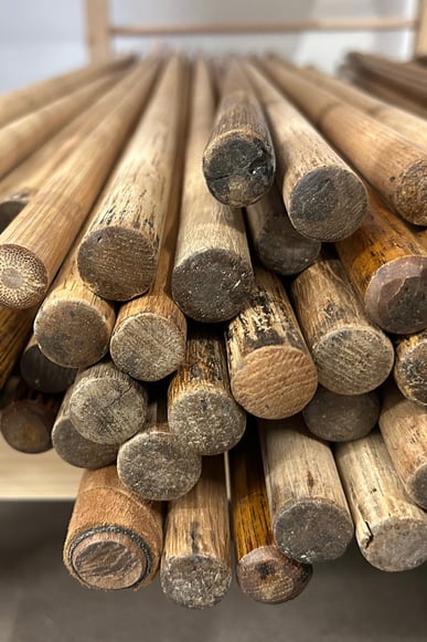 Close-up of cleaned and restocked original hickory shafts, showing aged wood, natural patina, and signs of previous use, stored on workshop shelves.