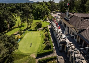 Aerial drone view of Villa d’Este Golf Club featuring the historic clubhouse, putting green, lush fairways, and panoramic mountain scenery in northern Italy.