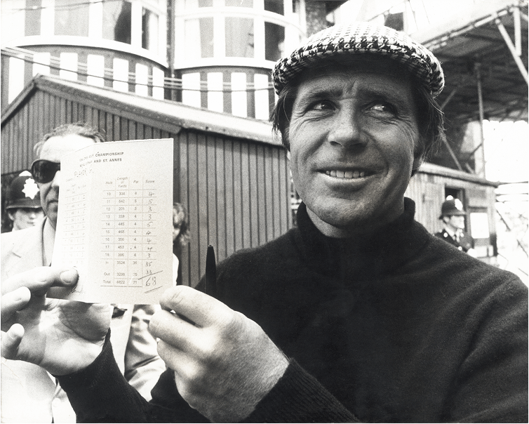 Gary Player smiling and holding his signed scorecard after a round at the Open Championship, with spectators and officials in the background. Gary Player smiling and holding his signed scorecard after a round at the Open Championship, with spectators and officials in the background.